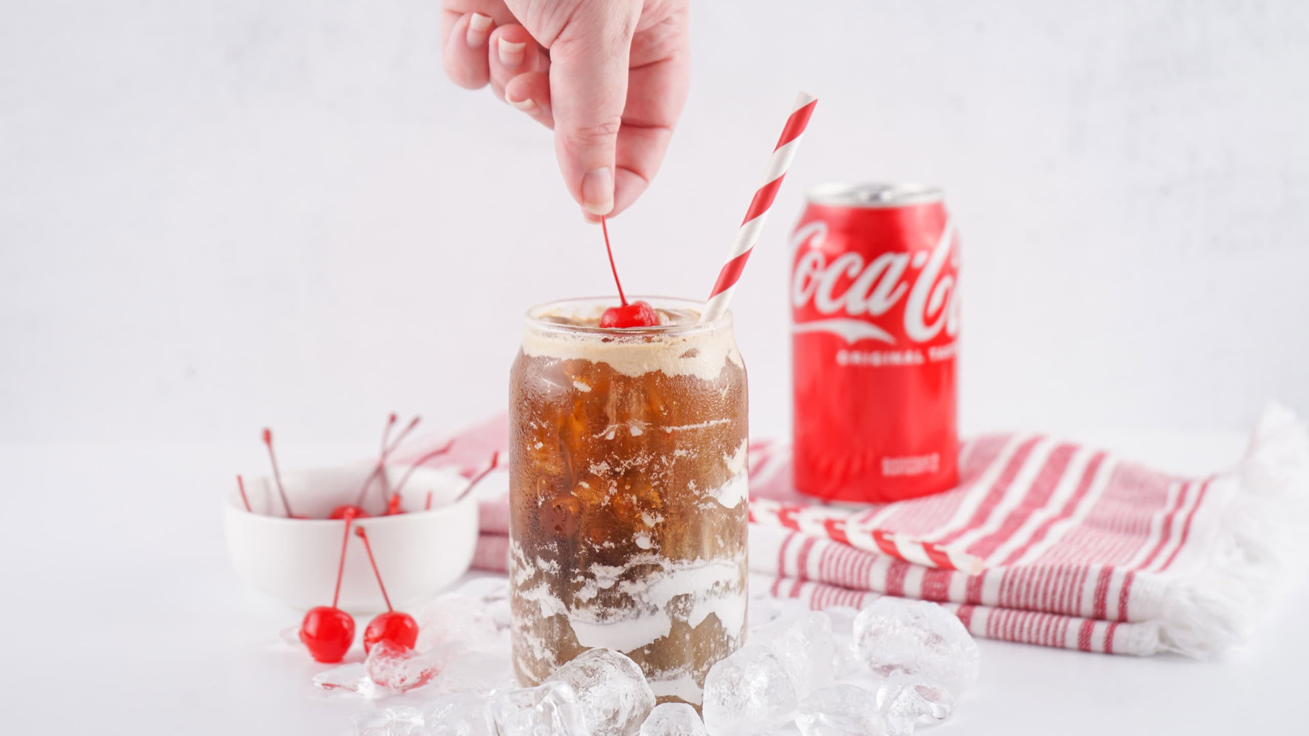 Placing a cherry on top of fluffy coke.