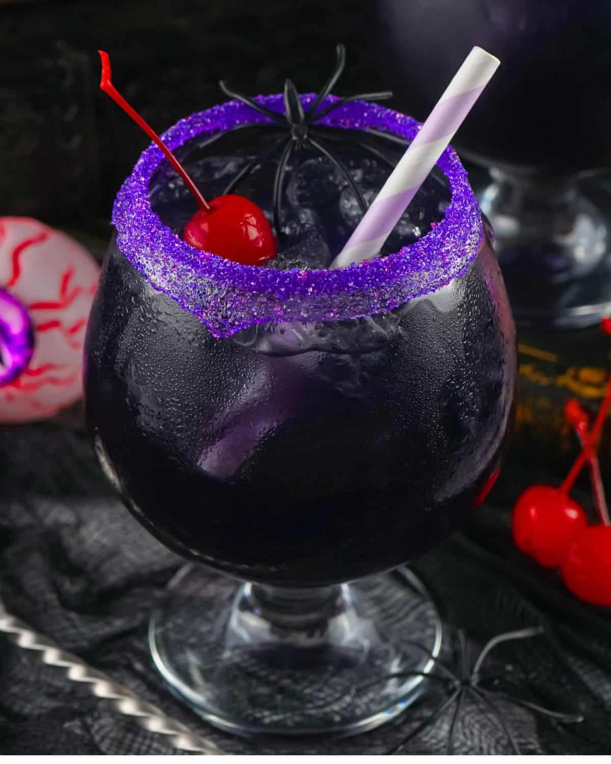 purple people eater cocktail with a purple sugar rim and a Maraschino cherry in it