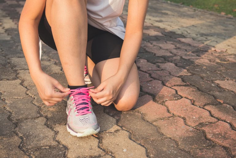 Woman lacing up running sneakers.