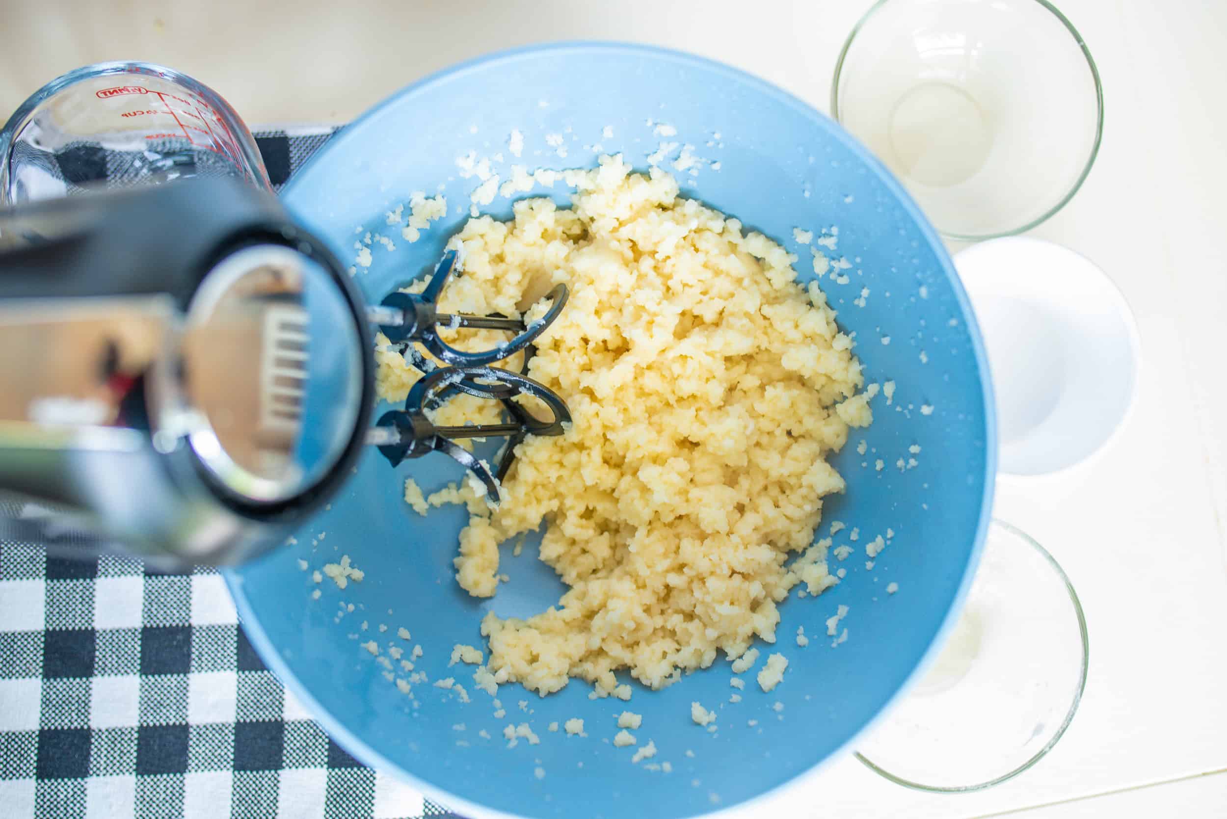 Blending churro dough in a blue bowl with a blender.