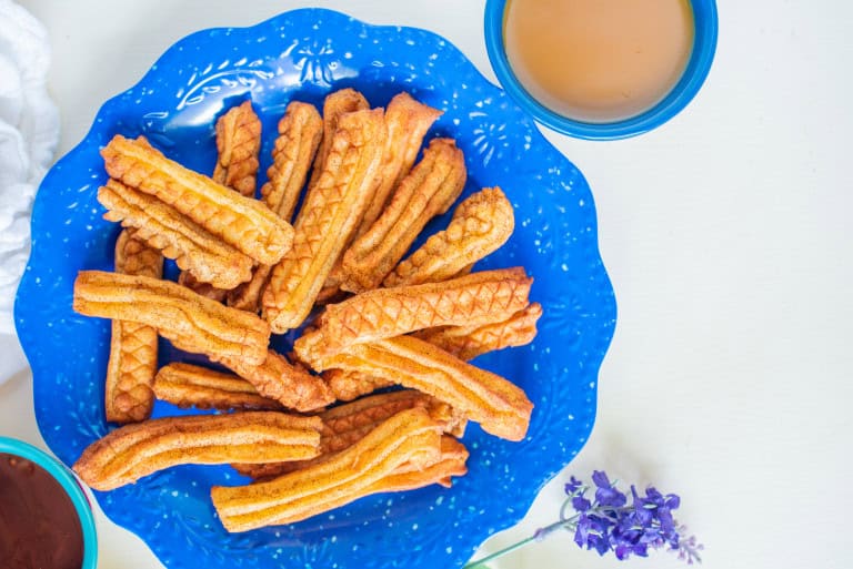 Overhead view of air fryer churros on a blue plate.