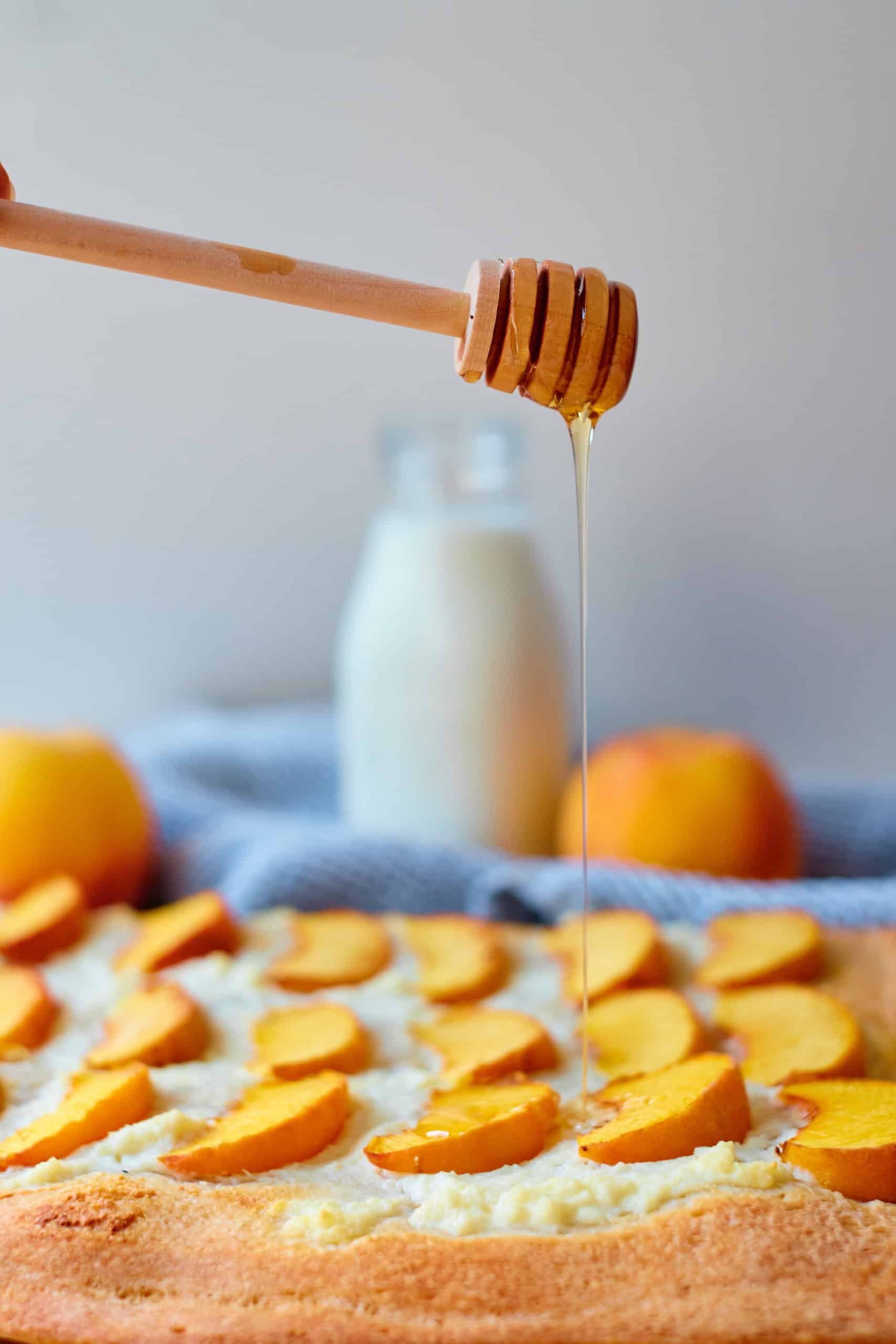 Drizzling honey on top of peach pizza with Ricotta cheese.