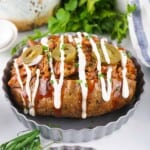 Pulled pork baked potato with BBQ sauce sour cream and pickled jalapenos on top.