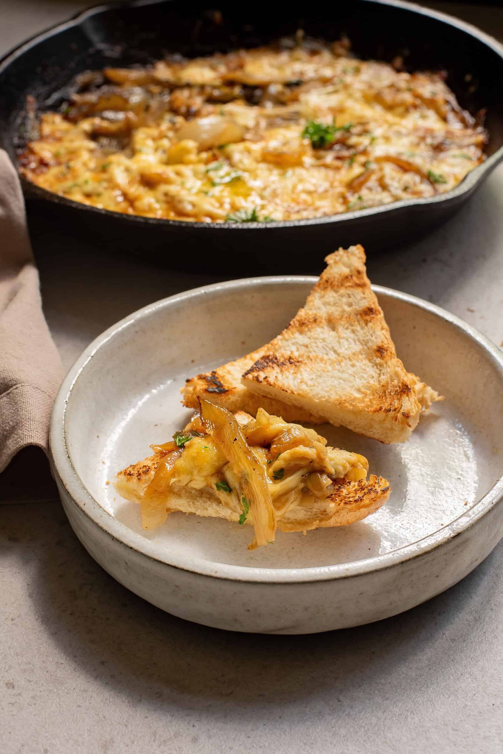 Baked French Onion Soup Dip served on a plate with triangle shaped toasts.