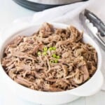 Bowl of pulled pork with diced green onions on top of it.