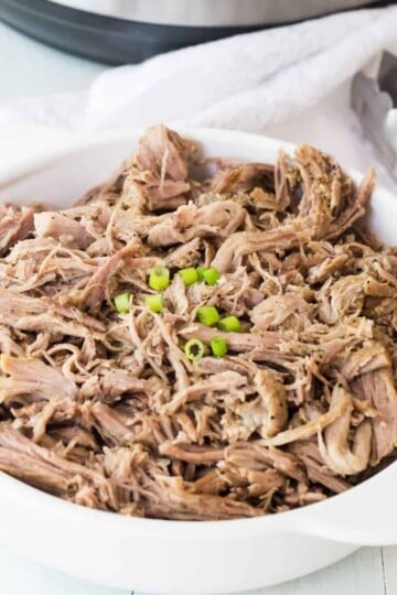 Bowl of pulled pork with diced green onions on top of it.