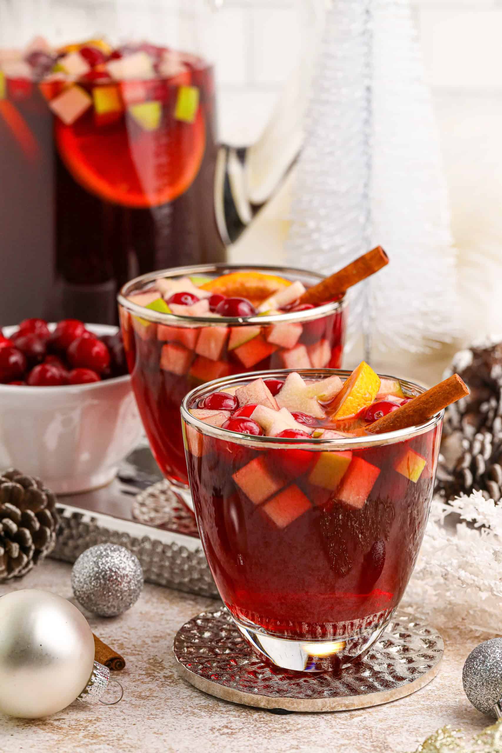 Headon view of 2 glass mugs filled with Holiday Sangria with cinnamon sticks in them.