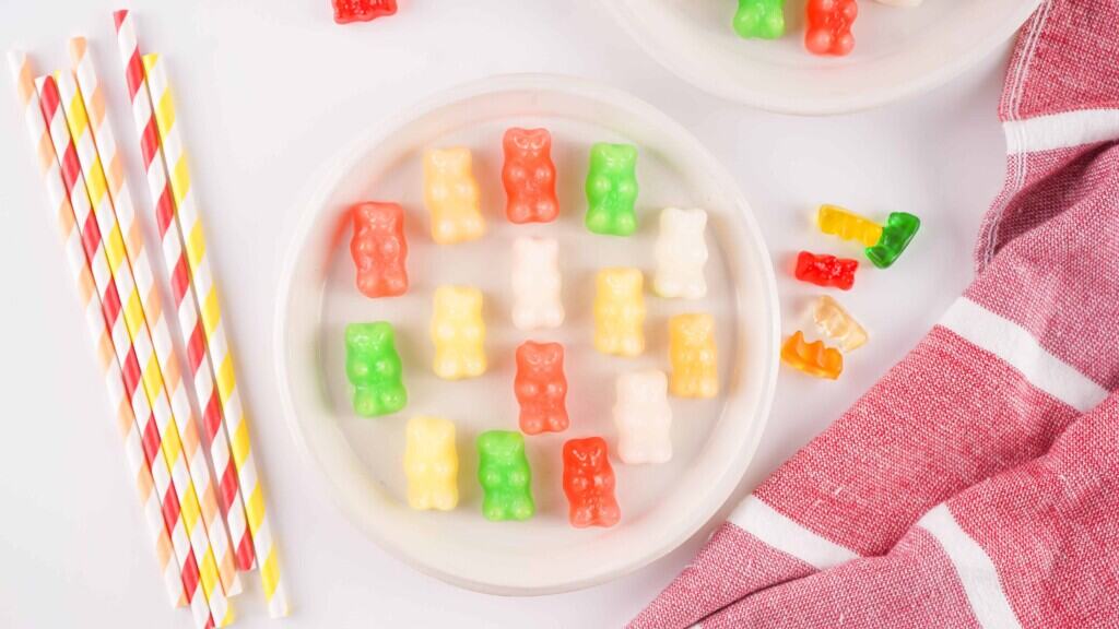 Overhead view of frozen gummy bears soaked in Sprite on a white plate