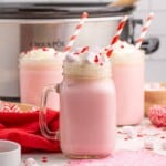 Pink hot cocoa with whipped cream and crushed candy canes on top.