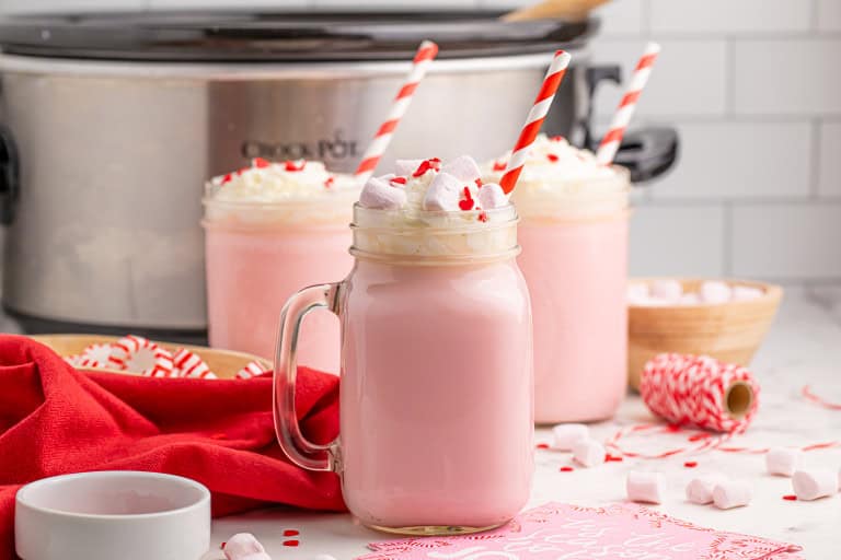 Pink hot cocoa with whipped cream and crushed candy canes on top.
