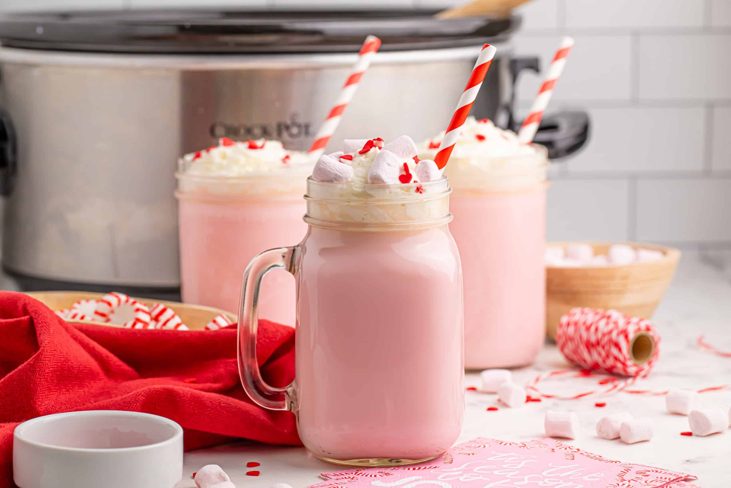 Pink hot cocoa with whipped cream and crushed candy canes on top.