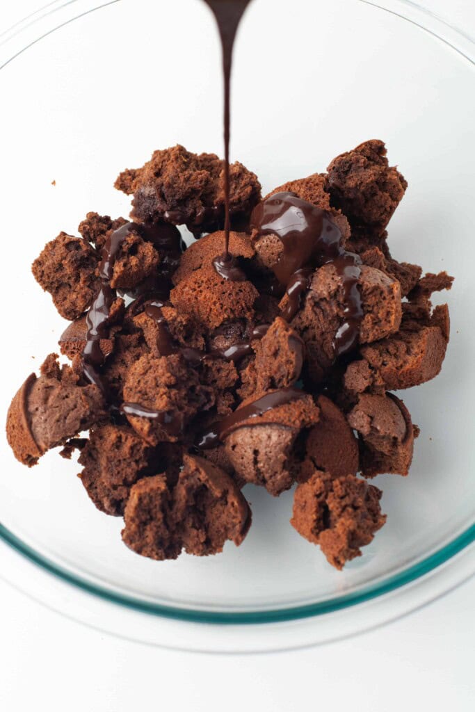 Crumbled brownies with chocolate auce being poured on them.