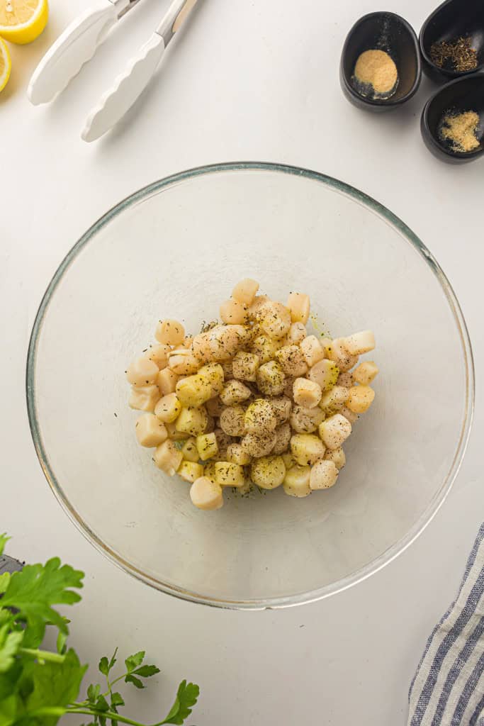 Overhead view of seasoned scallops in bowl.