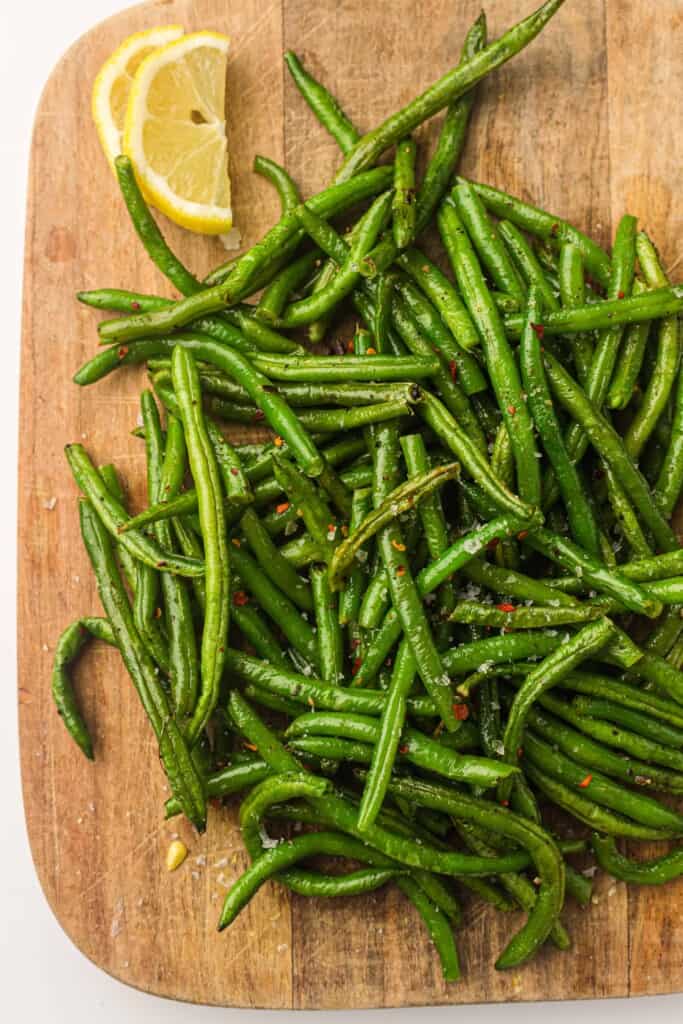 Overhead view of air fryer green beans on a cutting board.