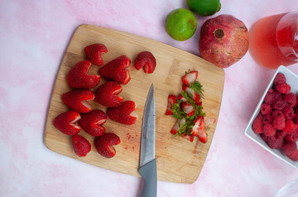 Overhead view of heart shaped strawberries on a cutting board.
