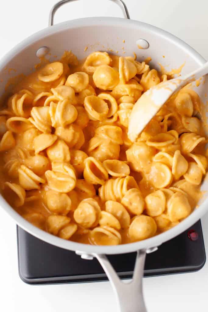Overhead view of Pasta alla Vodka in pan with a white spoon in it stirring the pasta.