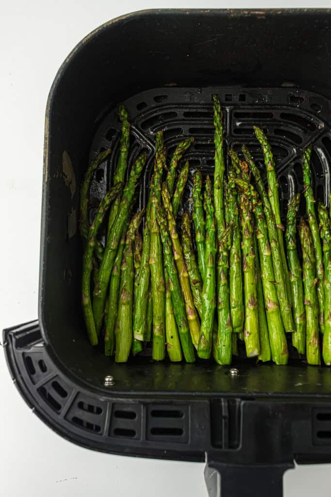 Overhead view of asparagus in air fryer basket.