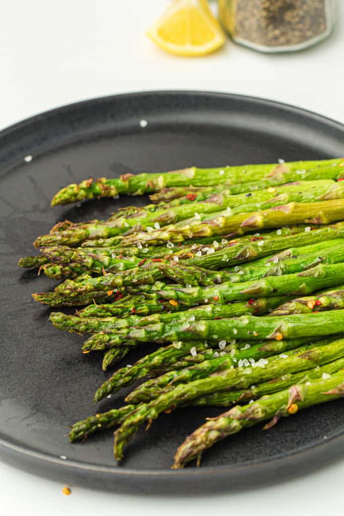overhead view of air fryer asparagus on a black plate.