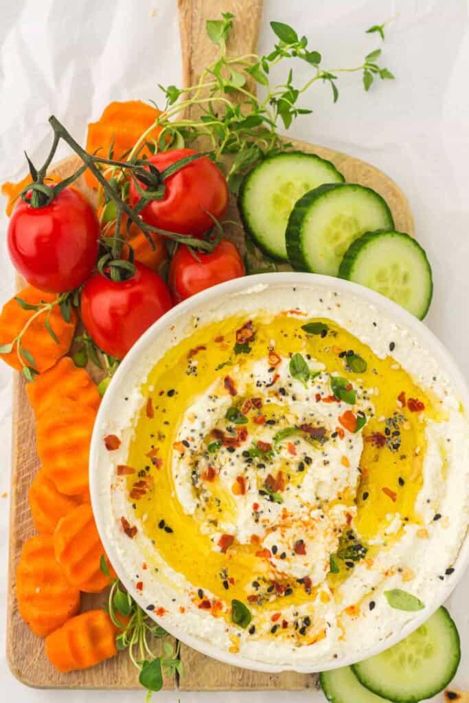 Feta dip served with fresh vegetables on a cutting board.