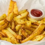 Homemade air fryer french fries with small cup of ketchup.