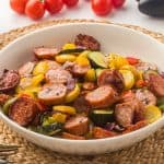 Oven roasted sausage and vegetables in a white bowl.