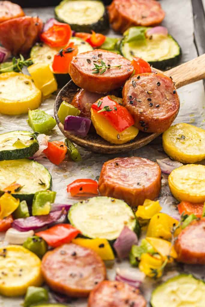 Overhead view of oven roasted kielbasa and peppers and zucchini on a sheetpan.