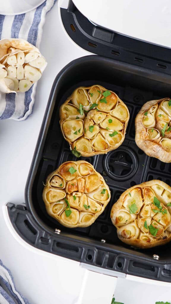 Overhead view of garlic bulbs in air fryer.