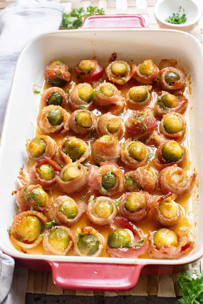 Overhead view of bacon wrapped Brussels sprouts in a casserole dish.