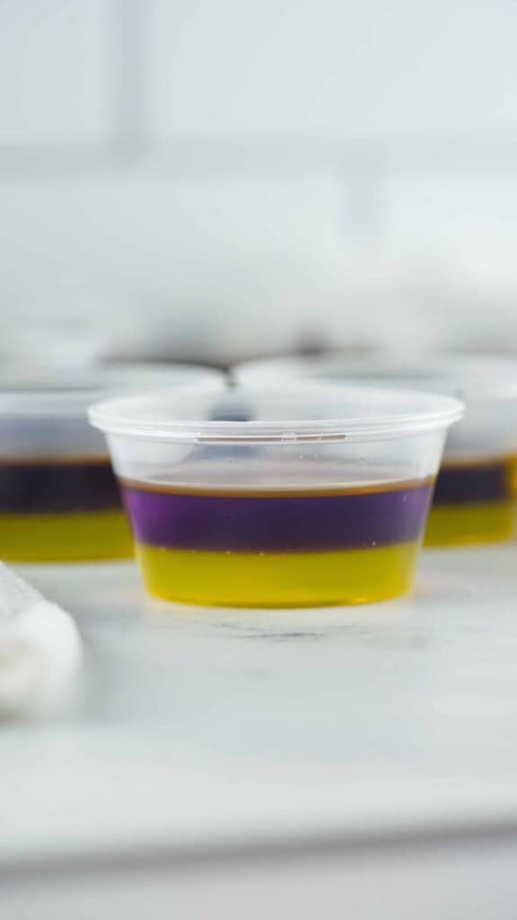 Lemon and grape layered jello in plastic shot cup.