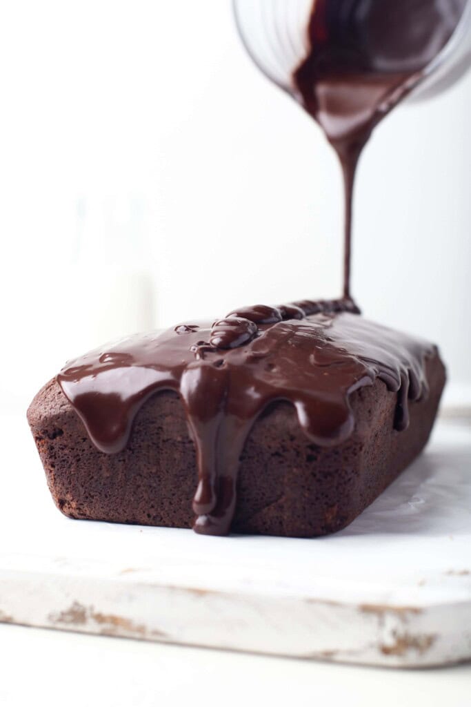 Pouring chocolate ganache on top of chocolate pound cake.