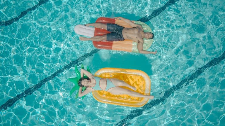 A man and a woman on separate rafts in a pool.