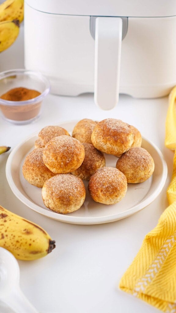 TikTok 2 ingredient banana holes on a white plate in front of the air fryer.