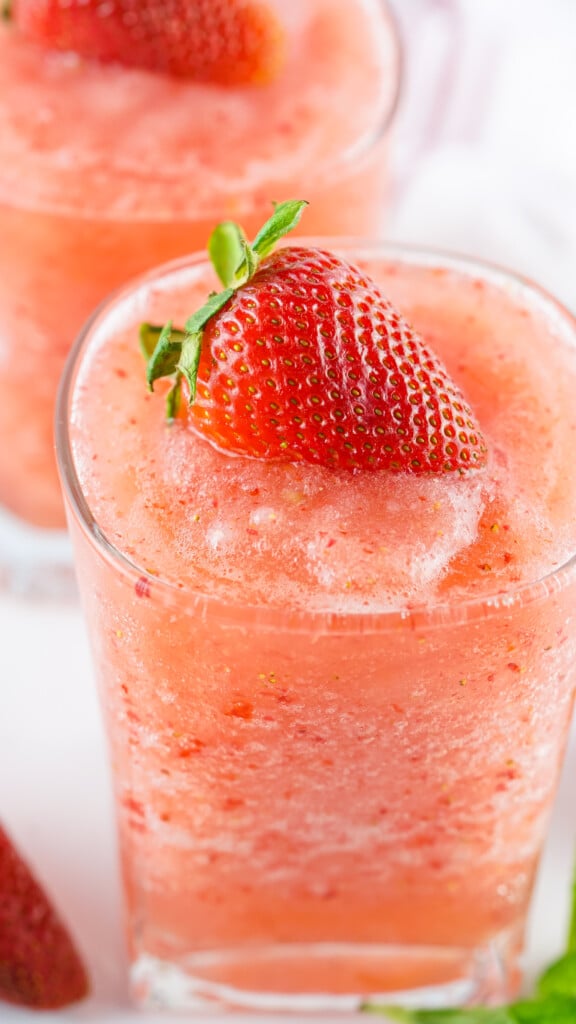 Closeup of Frozen Strawberry Ague Fresca in a tumbler glass with a fresh strawberry on top.