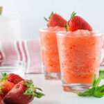 Headon view of 2 tumbler glasses filled with strawberry fresca topped with fresh strawberries.