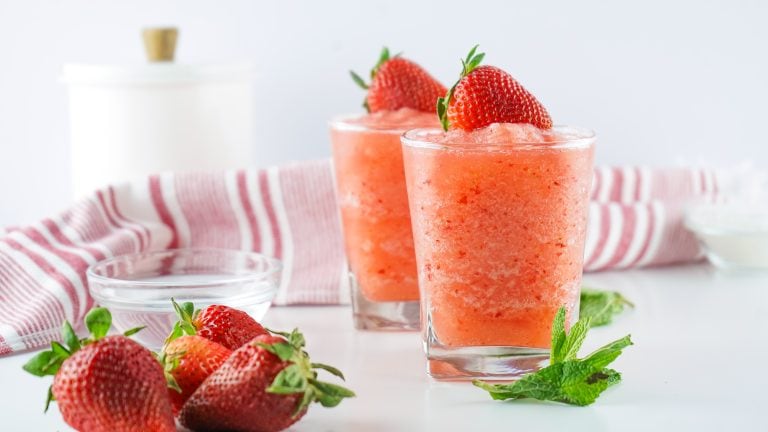 Headon view of 2 tumbler glasses filled with strawberry fresca topped with fresh strawberries.