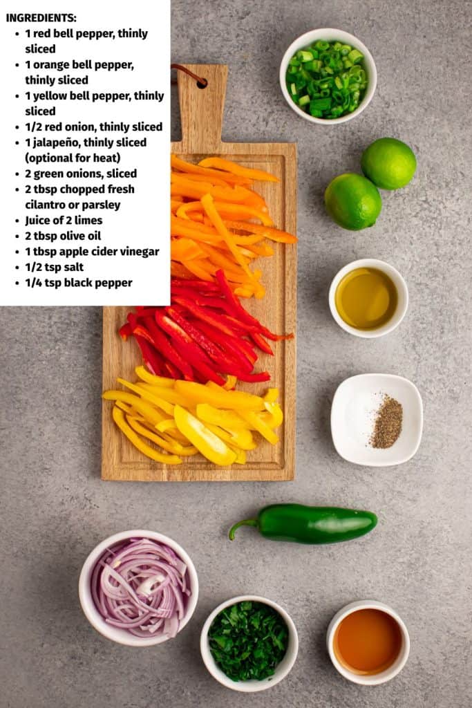 Overhead view of ingredients for Bell Pepper Slaw. Red, orange and yellow bell pepper slices on a cutting board. Two lines, oil, salt and pepper, sliced red onion and whole jalapeño on a stone counter top.