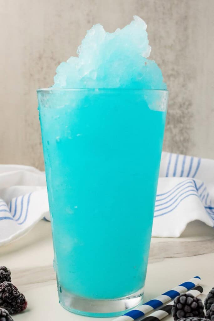 Homemade blue Gatorade slushy made with Glacier Freeze in a tall glass with frozen blackberries