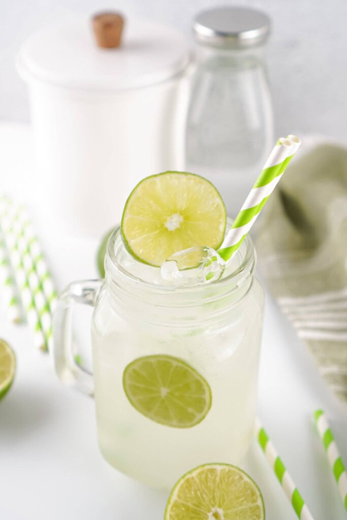 Homemade limeade in a mug with striped green straws.