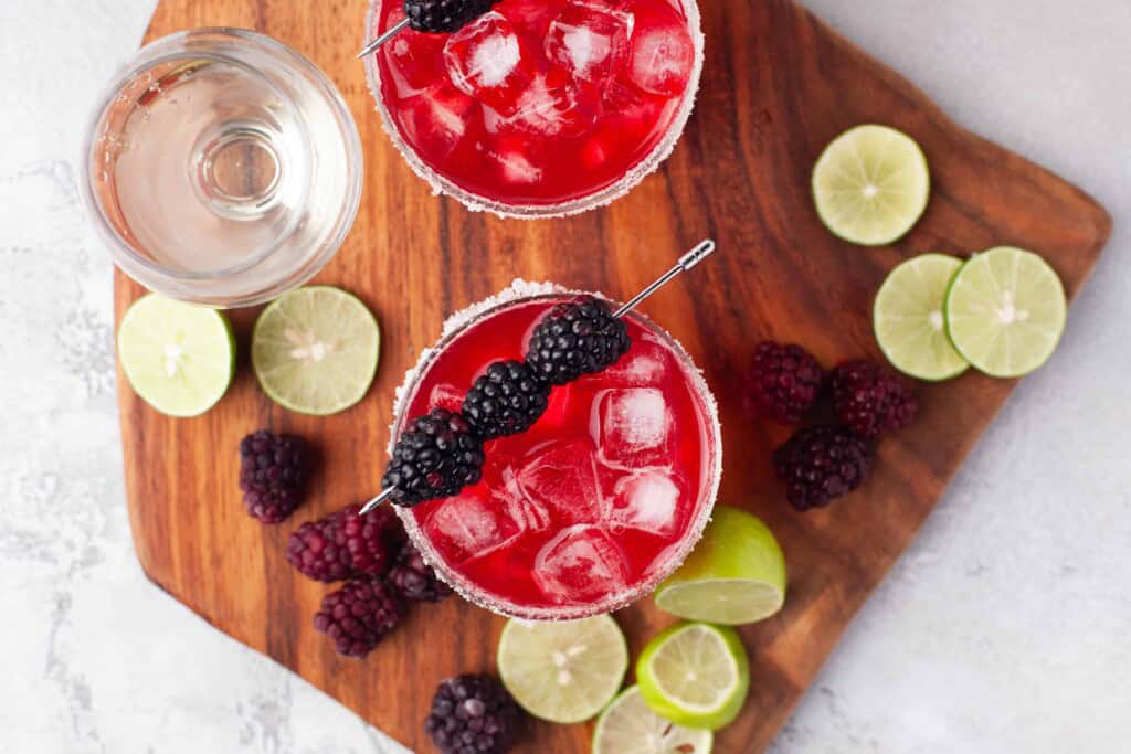 Overhead view of blackberry margaritas with lime slices.