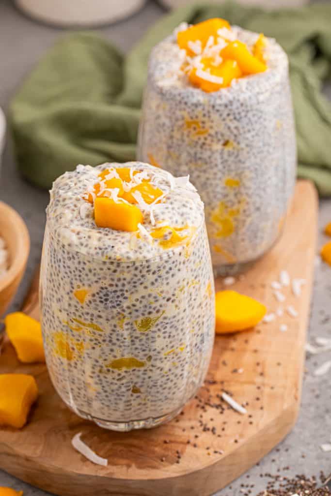 2 glass cups of mango chia pudding topped with mango chunks.