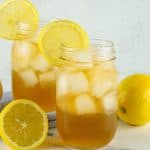 Head-on view of 2 Arnold Palmer Cocktails in glasses filled with ice with lemon slice garnishes.