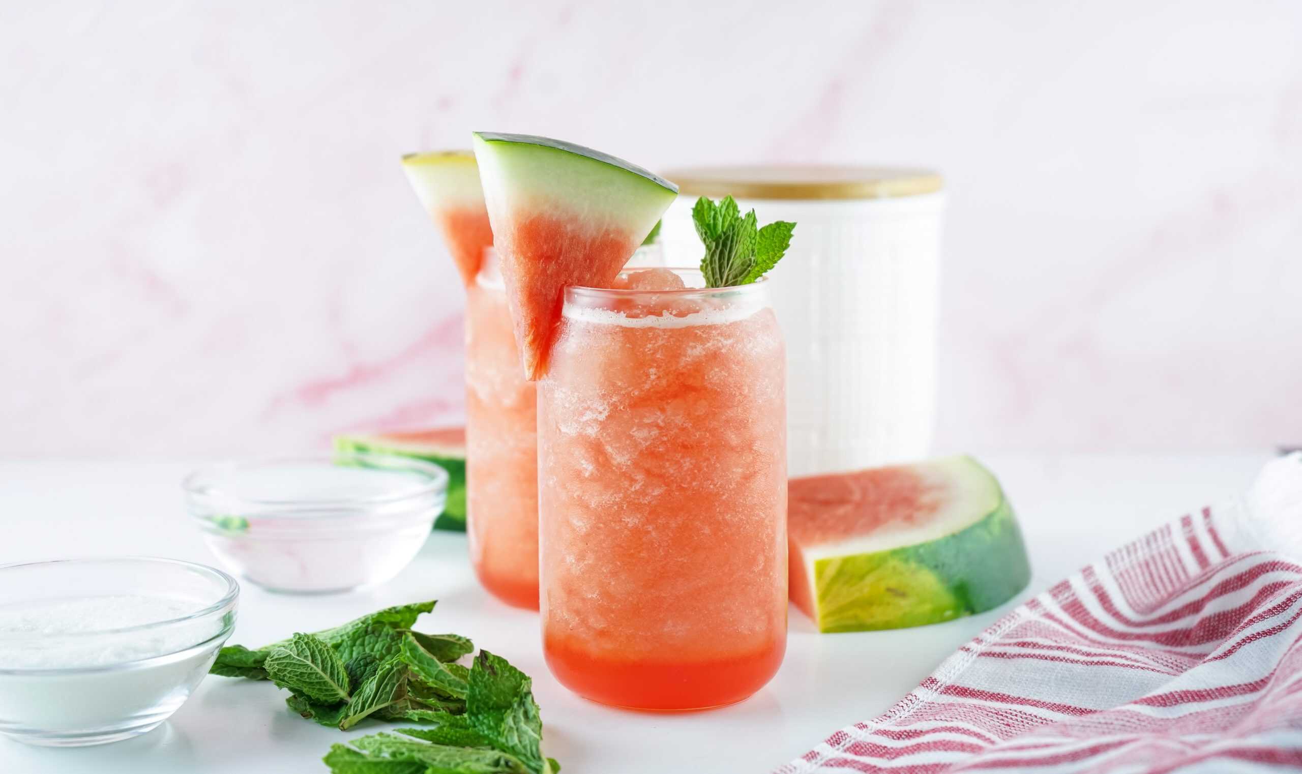 Head on view of watermelon Agua Fresca with a sprig of mint and watermelon slice for garnish.
