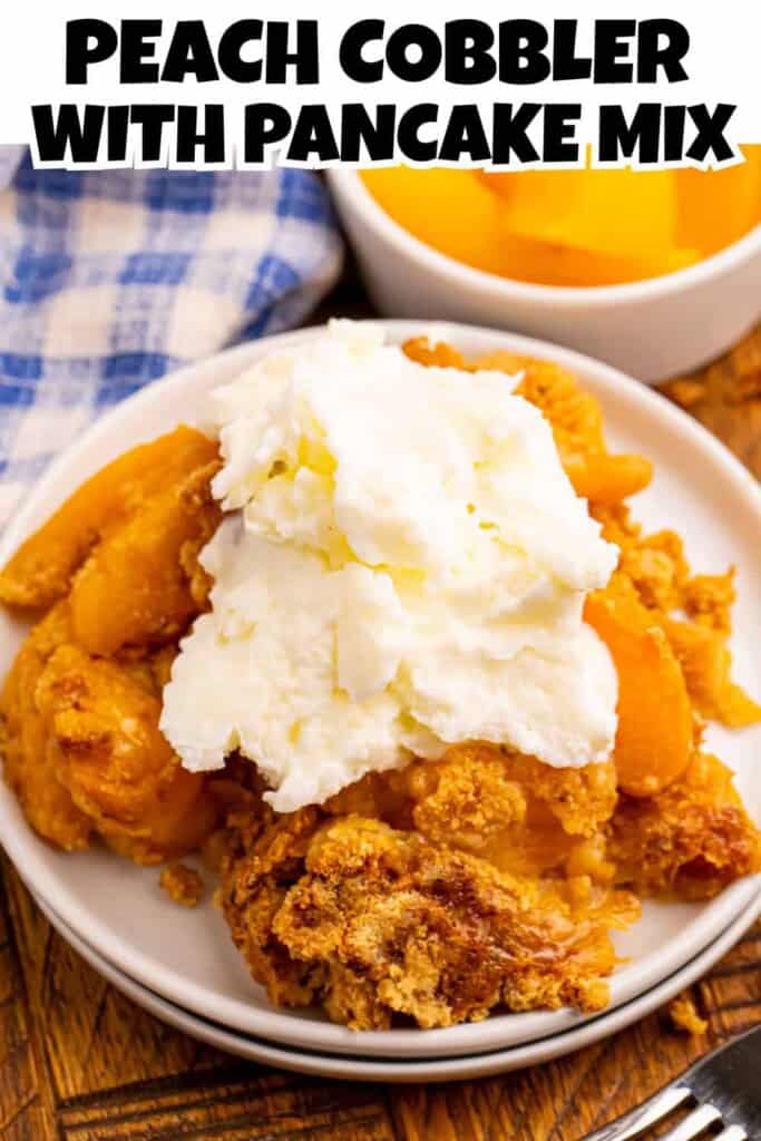 Overhead view of peach cobbler made with pancake mix on a white plate topped with vanilla ice cream. A bowl of peaches in the background with a blue and white checked dish towel. Text overlay on top for Pinterest.