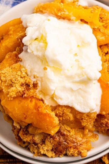 Overhead view of peach cobbler made with pancake mix with ice cream on top on a white plate.