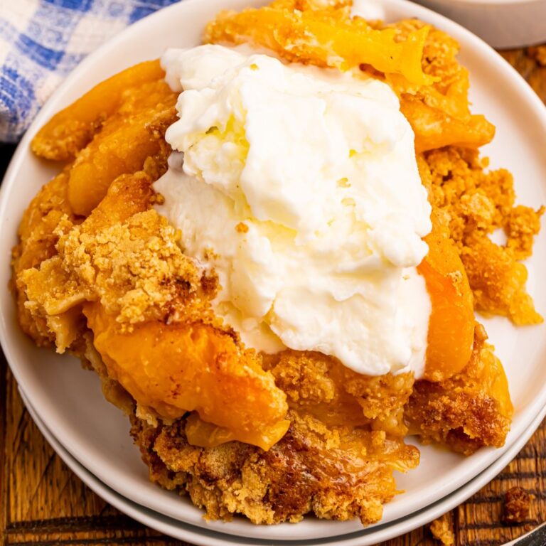 Overhead view of peach cobbler made with pancake mix with ice cream on top on a white plate.