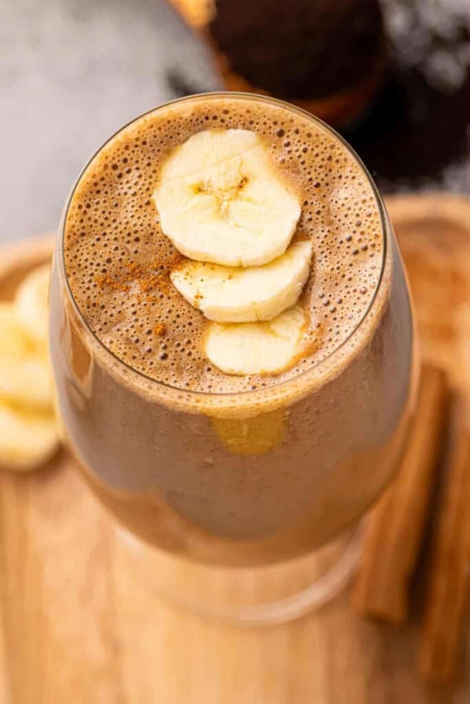 Coffee smoothie in a glass with banana slices on top.