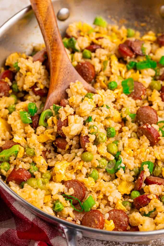 overhead view of hot dog fried rice in a skillet with a wooden spoon.