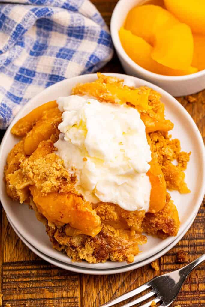 Overhead view of peach dump cobbler on a white plate served with vanilla ice cream.