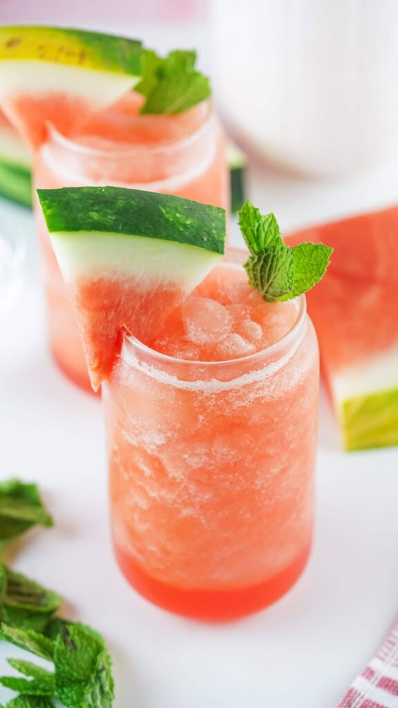 Overhead view of frozen watermelon Agua Fresca with watermelon wedges and sprigs of fresh mint. 