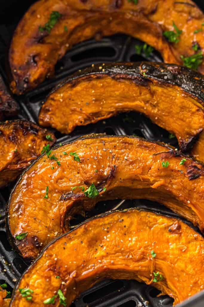 Overhead view of roasted pumpkin slices in the air fryer.